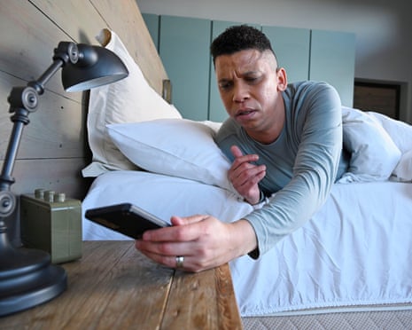 Man looking at smartphone in bed