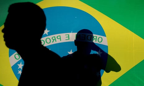 Silhouettes of people against a Brazilian flag