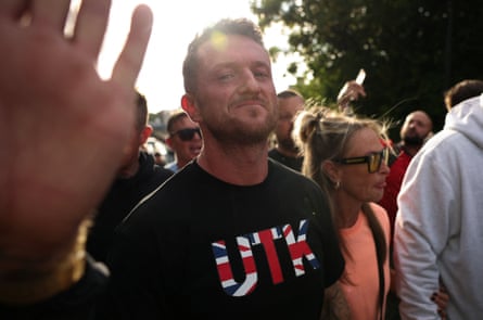 Tommy Robinson marching wearing a black T-shirt with a Union flag logo