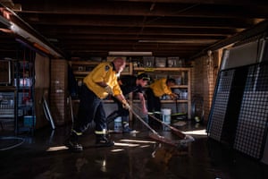 Residents and RFS personnel help clean up a flooded room in a house affected by the flood in Windsor.