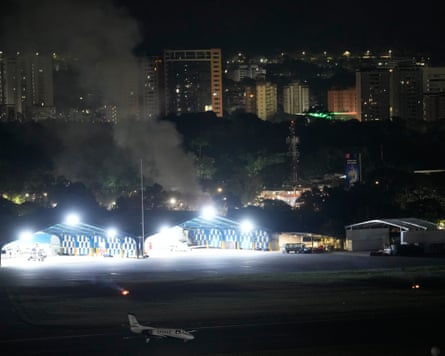 Aircraft in hangars with plume of smoke above