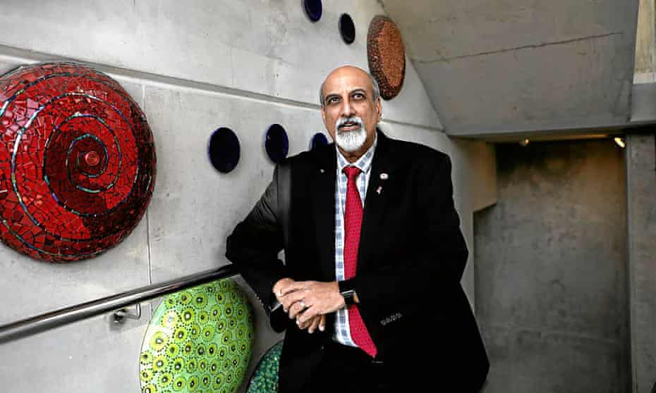salim abdool karim poses for a photograph leaning on a rail by ornate mosaic work on a concrete wall