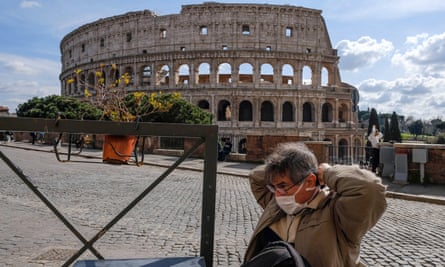 A tourist wearing a mask sits by the Colosseum in Rome on Monday, the day before the lockdown came into effect.