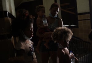 Residents wait to be served a plate of food donated by aid groups inside an occupied building in Rio de Janeiro