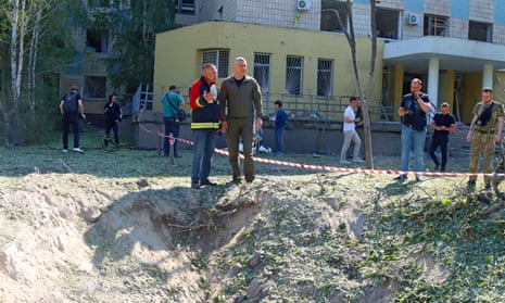 The mayor of Kyiv, Vitali Klitschko, stands on the edge of a small crater with an official
