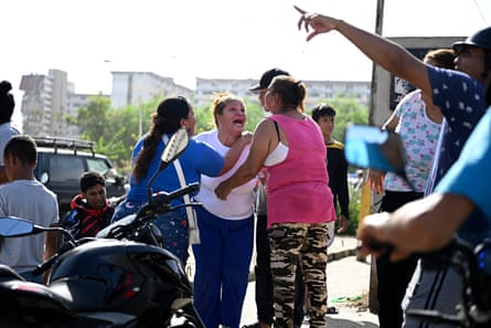 People react in anguish near a damaged apartment building in Catia La Mar.