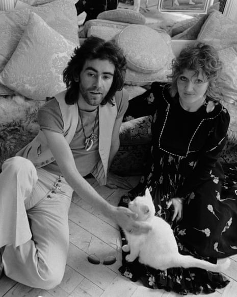 Ossie Clark and Celia Birtwell sit on a cushioned floor, he petting a white cat