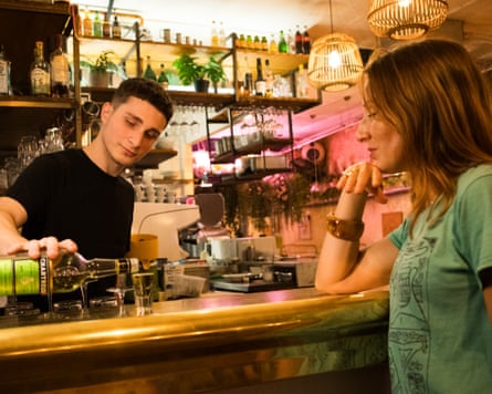A man standing behind the bar pouring a drink, with a woman on the other side of the bar