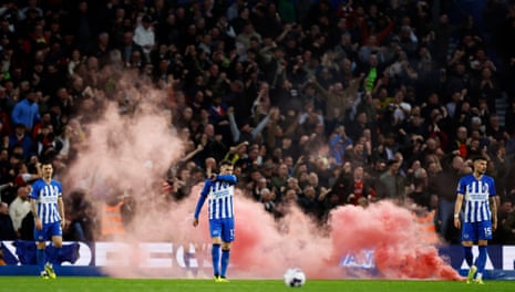 A smoke flare is thrown on the pitch as Brighton players look dejected after Arsenal's Kai Havertz scores their second goal.