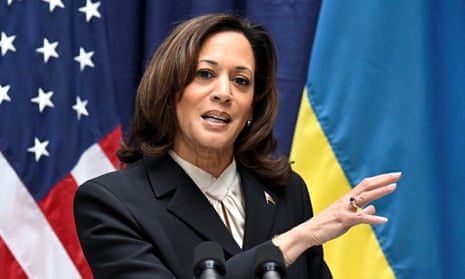 Black-Asian woman with shoulder-length black hair in dark suit, standing at podium and speaking.