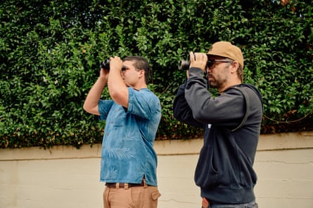 two men peer through binoculars