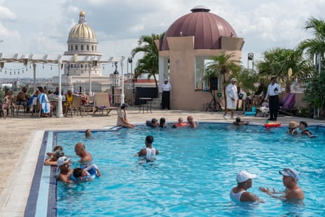 People enjoying a hotel swimming pool with the Havana skyline in the distance.