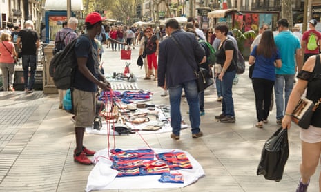 Tourists look at the wares of the manteros in Barcelona, Spain.
