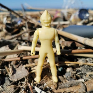 A plastic alien figurine on the beach.