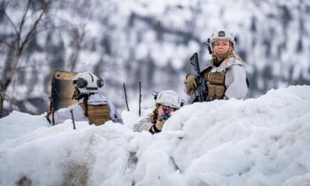 Soldiers looking over a snowy bank with trees in the background
