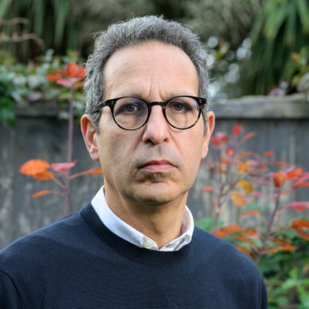 Enver Solomon photographed in his garden wearing a blue jumper