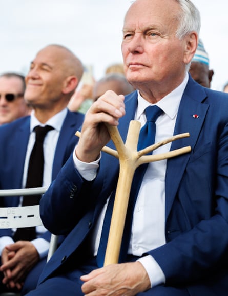Ayrault seated holding wooden stick