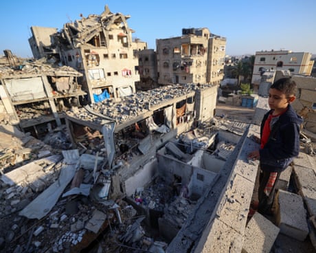 A boy looks at destroyed buildings