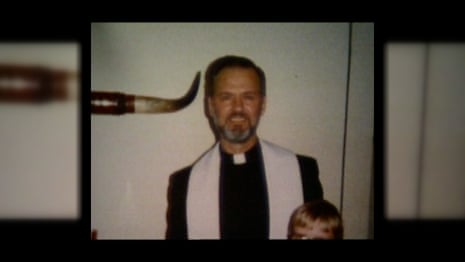 A man in clerical attire with a white stole smiles with a child beside him