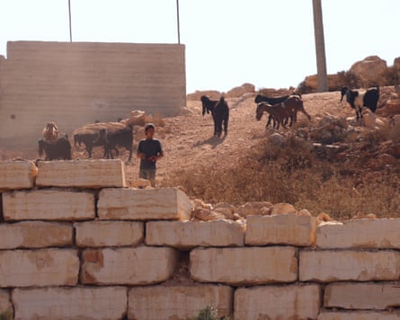 An Israeli settler leads his sheep as settlers besiege a Palestinian home.