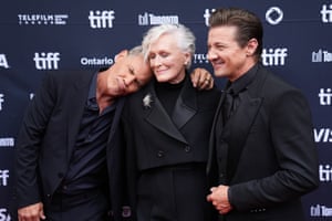 Josh Brolin rests his head on Glenn Close's shoulder and Jeremy Renner stands beside, all of three of them dressed in black