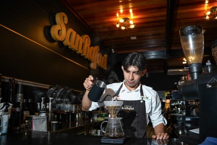 A barista wearing an apron pours water through a coffee filter at Café San Rafael