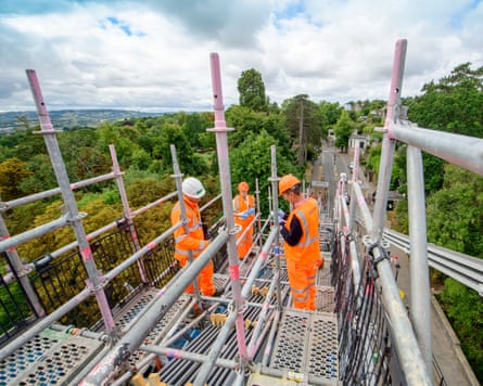 Men in hi-vis clothing stand high up on scaffolding on the Clifton Suspension Bridge