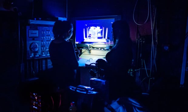 Two stage managers in the wings of a theatre production looking at a video monitor of the performance