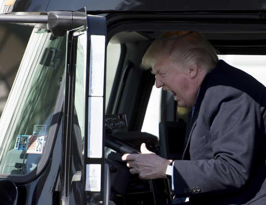 Donald Trump sits in the driver’s seat of a vehicle as he welcomes truckers and CEOs to the White House on 23 March