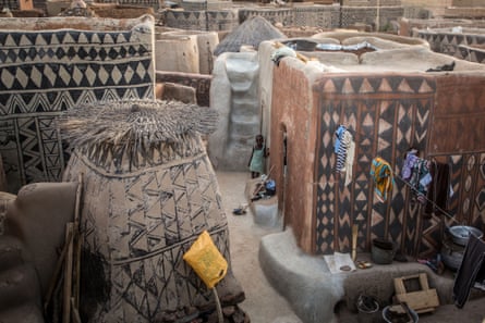 A child stands among intricately painted houses.
