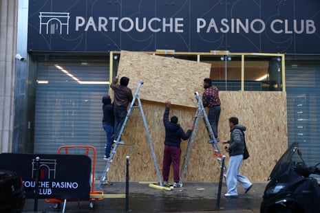 Workers install wooden panels to protect the windows of the gaming club Partouche Pasino Club in Paris