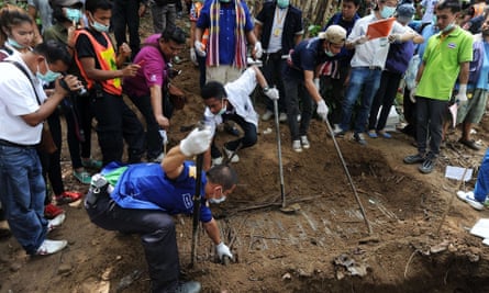 Rescue workers and forensic officials exhume skeletons from shallow graves covered by bamboo in Thailand’s southern Songkhla province.