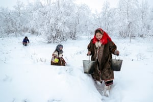A woman with children gathers snow for melting  in the village of Gornoknyazevsk. Nomadic indigenous peoples of northern Russia live in chums – round tent-like dwellings made of wooden poles and reindeer hides, with a fireplace in the middle.