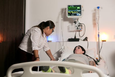 woman leans over patient in bed with medical equipment nearby