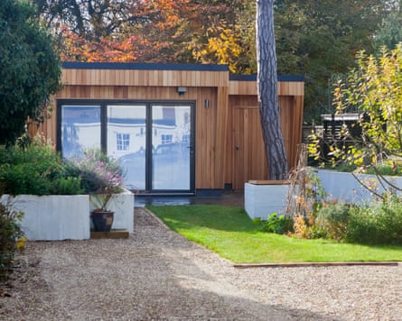 A bespoke garden office with bifold doors in a pretty garden.