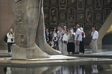 Tourists stand beside two huge stone feet