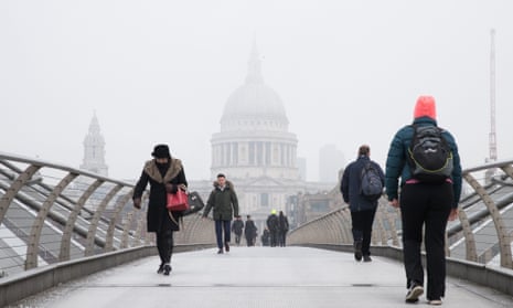 People cross the Millennium Bridge in London near St Paul’s while freezing fog covered the capital on Monday.