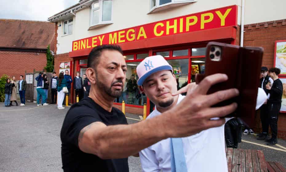 The TikTok star J2Hundred (right) poses outside Binley Mega Chippy in Coventry as people queue to order their food