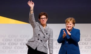 Annegret Kramp-Karrenbauer waves next to German Chancellor Angela Merkel after being elected as CDU party leader.