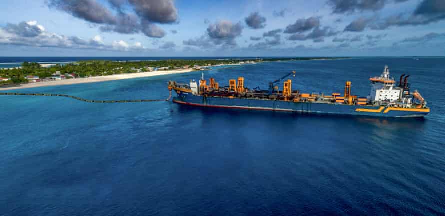 A big ship with a pipe between the bow and a tropical island 