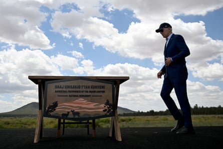 a man in a suit and baseball camp walks in a grassy area