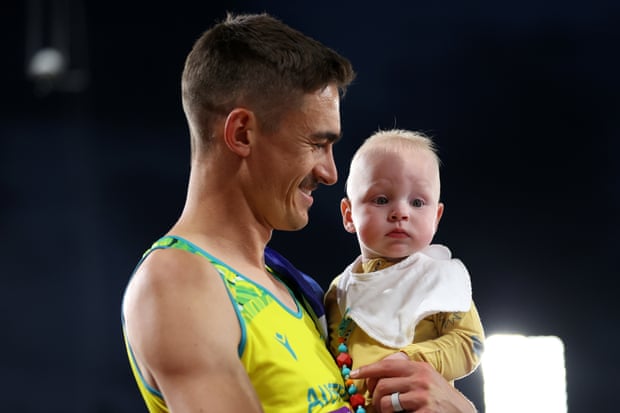 Brandon Starc spends a few moments with his baby after winning the silver medal in the high jump.
