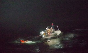 Japan Coast Guard officers rescue a crew member of the cargo vessel that sank off southwestern Japan