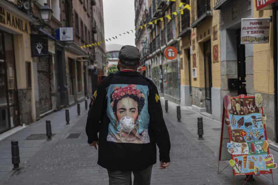 A man wearing a customised jacket with the image of Mexican artist Frida Kahlo wearing a face mask walks through central Madrid, Spain