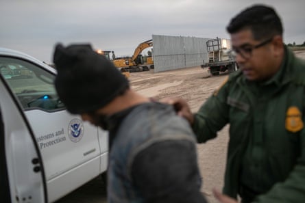 A border patrol agent detains an undocumented immigrant near a section of privately-built border wall under construction on 11 December 2019 near Mission, Texas.
