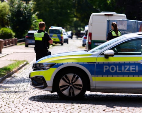 German police vehicles and officers patrol an area near a mass shooting in Stade