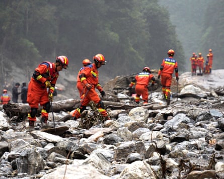 Firefighters in safety gear looking through rubble.