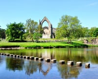 Stepping stones over river and ruins of a religious building on a sunny day