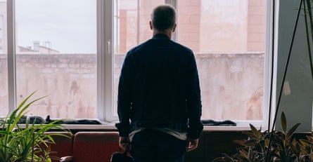 The silhouette of a man from behind looking out of a window.