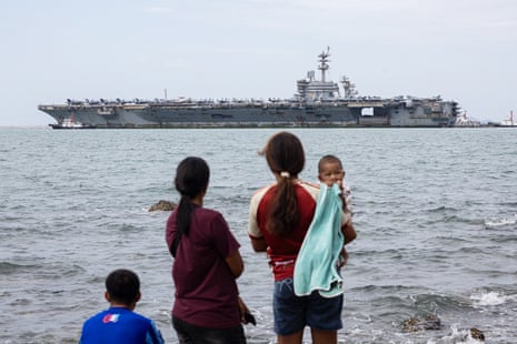 A family looks at a large ship sailing by.